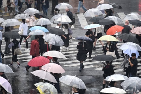 A crowded Tokyo crossing filled with people holding colourful umbrellas in the rain