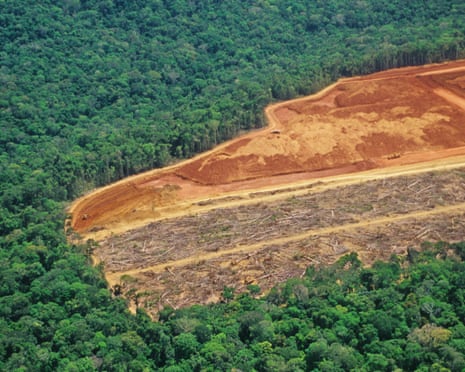 Aerial view of deforested, reddish-brown land cut into the dense Amazon rainforest